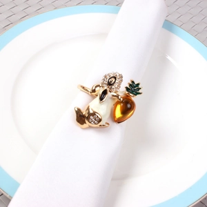 Golden metal bunny napkin ring with white enamel and amber carrot on a white napkin