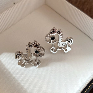 Detailed macro view of silver horse earrings with black gem eyes in a white jewelry box