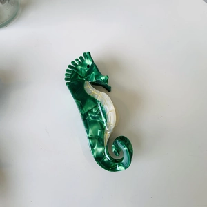 Detail of seahorse claw clip featuring green marble acetate texture on white background