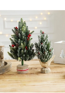 Detail of mini snowy Christmas trees with red berries and rustic burlap wooden bases