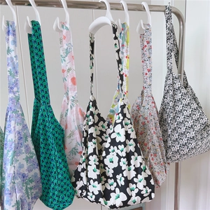 Detailed display of large capacity floral cotton tote bags hanging on a minimal rack
