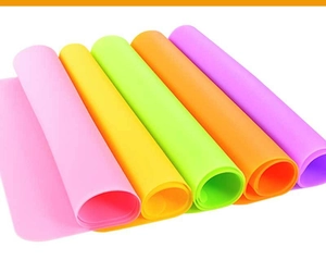 Multiple colorful silicone placemats rolled up showing flexibility and vibrant color variety