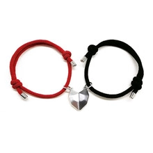 Close-up of adjustable magnetic couple bracelets in red and black woven rope with heart charm