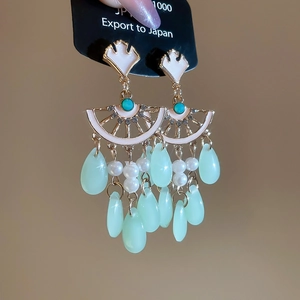 Detail of ginkgo leaf tassel earrings with green teardrop pendants and blue beads