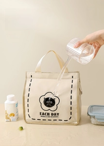Waterproof cream lunch bag with cat print showing liquid rolling off the surface