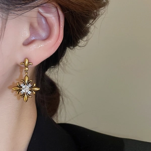 Close-up of vintage gold fleur-de-lis earrings with zircon stones worn on ear