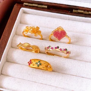 Close-up of vintage gold-plated flower and crown rings with gemstone details on white velvet