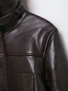 Detail of dark brown faux leather jacket featuring glossy texture and plush faux fur lining