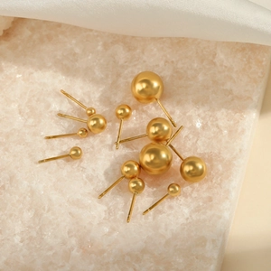Minimalist gold ball stud earrings in multiple sizes on elegant white stone background