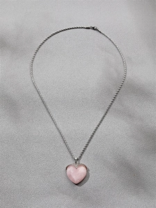 Detail of pink heart crystal pendant with silver edge on twisted rope chain necklace