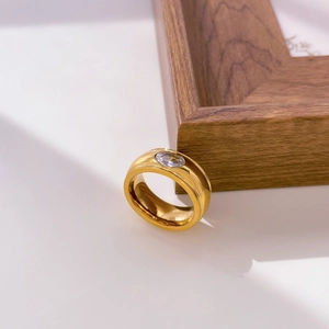 Macro shot of gold-plated wide band ring with a bezel-set oval cubic zirconia stone