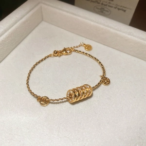 Detail eines 18k vergoldeten Armbands mit Münzanhängern und Edelsteinzylinder in weißer Box