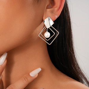 Detail view of silver geometric hollow rhombus earrings with pearl on female model