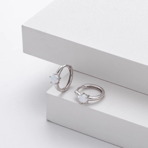 Detailed view of silver hoop earrings featuring white opal stones and secure four-prong setting