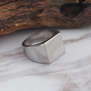 Polished silver square signet ring in titanium steel on a marble and wood surface