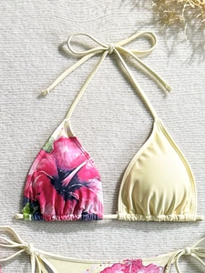 Flat lay of a bikini top featuring pink hibiscus floral print and cream mesh panels