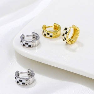 Macro shot of gold and silver checkerboard hoop earrings with star relief details on white silk