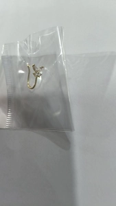 Detail of a golden non-pierced U-shaped nose clip with a butterfly design and zircons