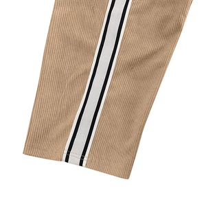 Macro detail of khaki corduroy fabric and black-and-white striped ribbon on trousers