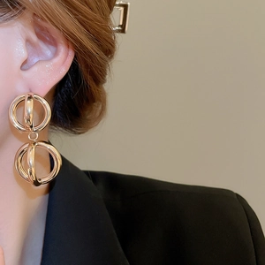 Orecchini a sfera cava geometrica in oro lucido indossati da una modella in stile business