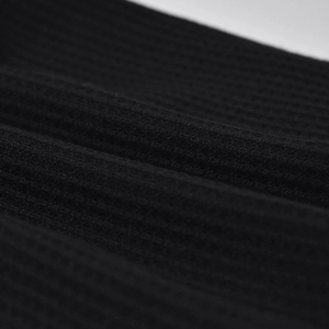 Macro detail of black waffle knit fabric showing texture and soft material density