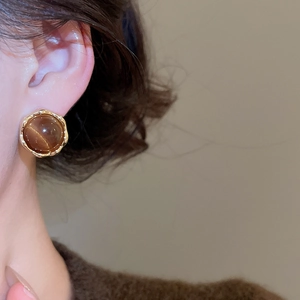 Close-up of 18k gold plated tiger eye stone stud earring on model's ear