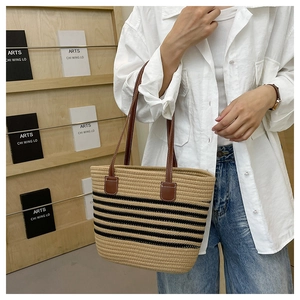Dettaglio della borsa tote in paglia kaki a strisce nere con manici in pelle marrone