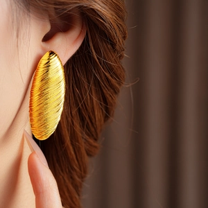 Close-up of golden curved textured hoop earring on model with elegant detail