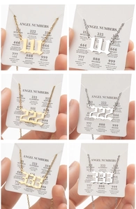 Detail of angel number pendants 111, 222, 333 in gold and silver stainless steel