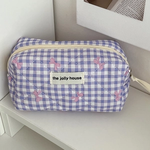 Close-up of purple plaid cosmetic bag with pink bow detail and quilted texture