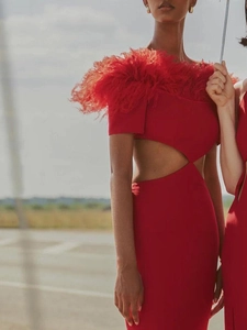 Detail of red off-shoulder dress featuring vibrant feather trim and waist cut-out accents