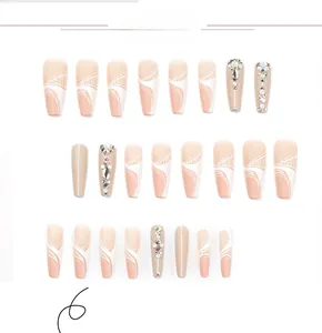 Macro view of long ballerina press-on nails with nude pink gradient and rhinestone accents