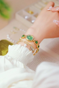 Close-up of gold women's watch with green dial and matching heart pearl bracelet