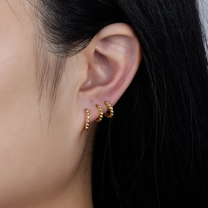 Three gold huggie hoop earrings with beads worn on ear for minimalist styling