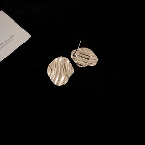 Macro shot of silver irregular water ripple stud earrings on black velvet background