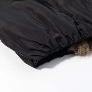 Detail shot of black glossy winter jacket with premium brown faux fur collar and elastic hem