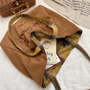 Detail view of large suede tote bag with plaid lining and retro embroidery