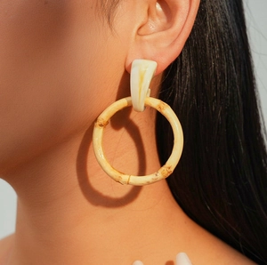 Detail of bohemian resin bamboo hoop earrings worn by a model in natural lighting