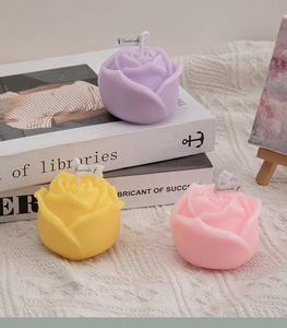 Detail of rose-shaped scented candles in purple, yellow, and pink on knit fabric