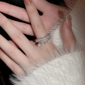 Gros plan d'une bague argentée double rangée avec oxydes de zirconium et cinq perles