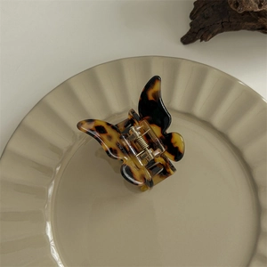 Detailed close-up of a leopard print butterfly hair claw clip on a ceramic tray