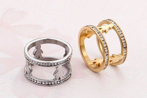 Close-up of dual-layer stainless steel couple rings with figure cutouts and crystals