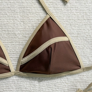 Detail shot of brown bikini top with beige trim on soft fabric background