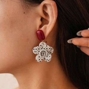 Close-up of vintage red oval studs and black and white polka dot flower pendant earrings