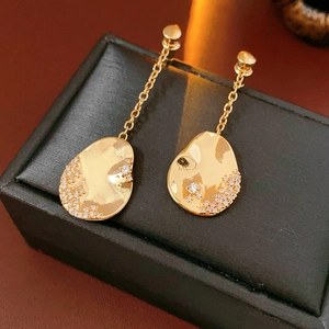 Vue détaillée des boucles d'oreilles asymétriques plaquées or 18k avec zircons brillants