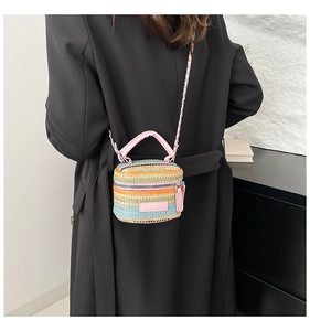 Dettaglio della borsa a secchiello in paglia colorata con manico in pelle rosa e catena