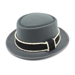 Macro detail of dark grey wool pork pie hat featuring a beaded black ribbon trim
