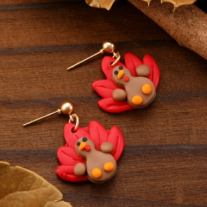 Detail of turkey clay earrings with golden hooks on autumn leaves and wood background