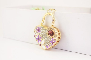Detail of heart keychain with red gemstone and floral motifs on a gold base
