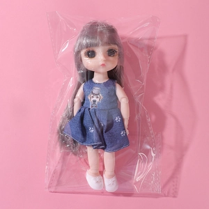 Close-up of 16cm doll with grey long hair wearing a blue denim dress on pink background